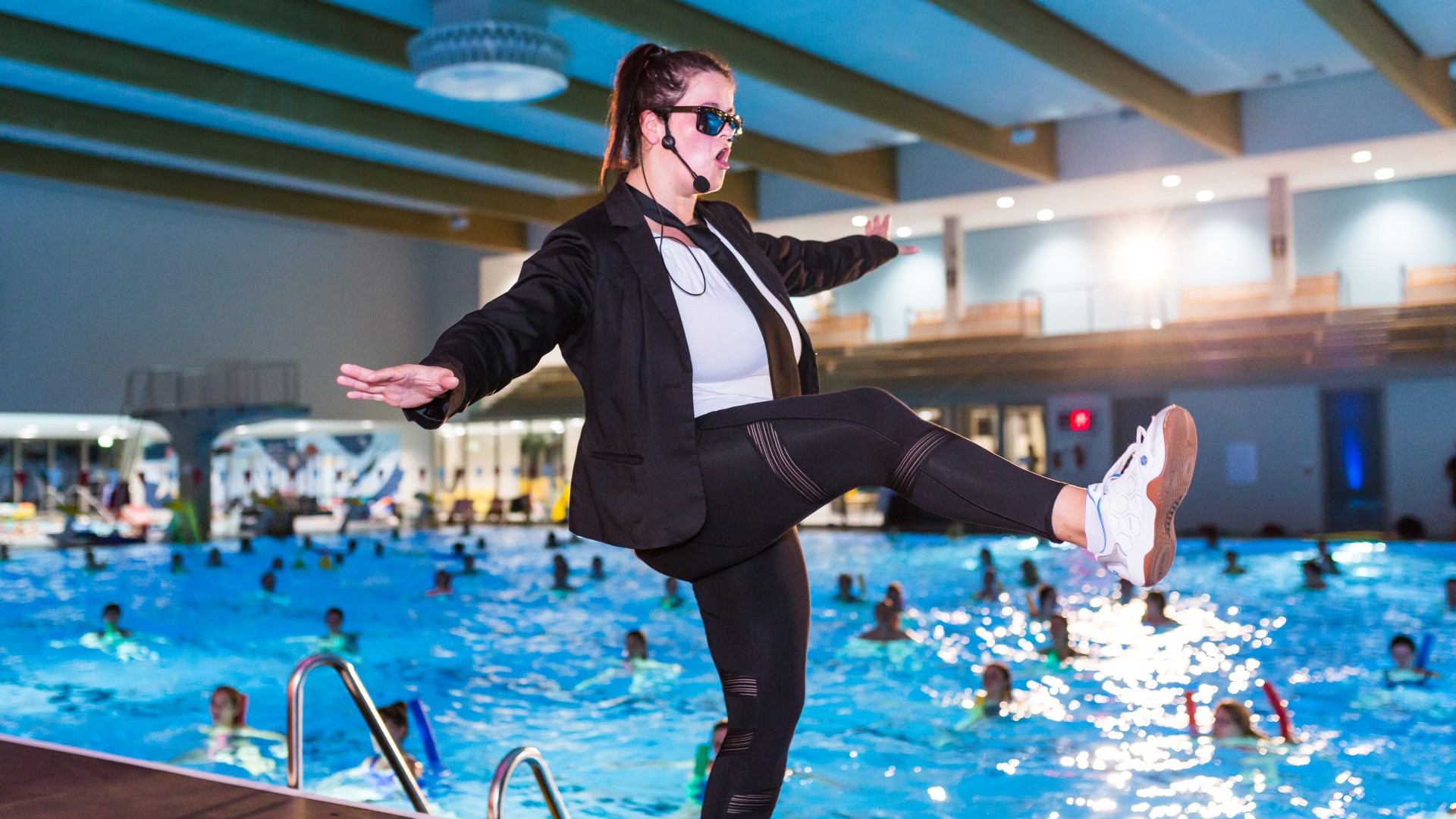 Auqafitness-Trainerin in schwarzer Kleidung mit weißem Shirt und Sonnenbrille Tanzt auf der Bühne der blu.AquaNacht, © SekundenstillFotografie