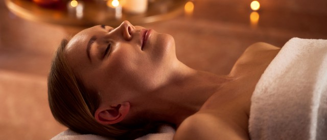 Junge Frau entspannt in der Sauna mit Kerzenschein, © Adobe Stock - Yakobchuk Olena