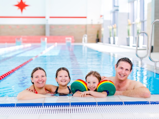 Familie mit zwei Kindern im Wasser am Beckenrand vom Kiezbad, © Alena Suber