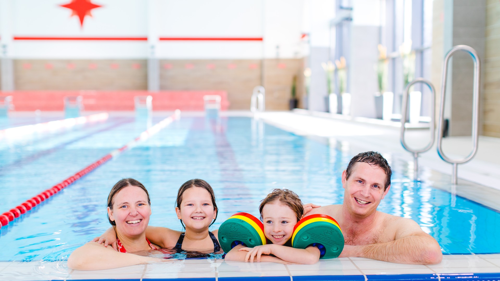 Familie mit zwei Kindern im Wasser am Beckenrand vom Kiezbad, © Alena Suber