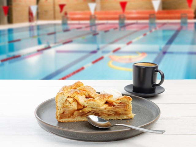 Ein Stück Kuchen und ein Kaffe stehen auf dem Tisch in der Schwimmhalle Kiezbad Am Stern