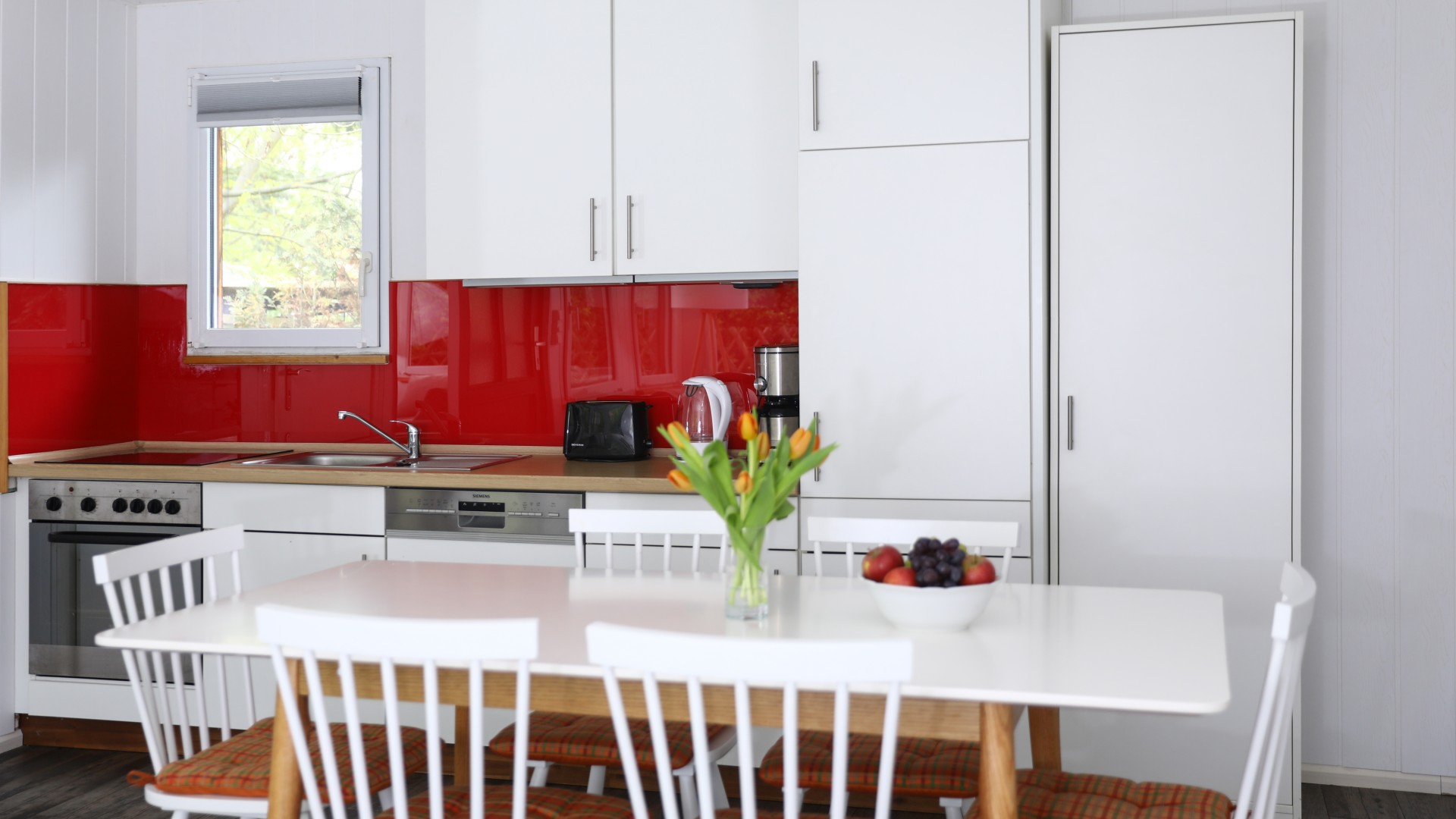 Weiße Küche mit roten Akzenten im Bungalow Waldbad Templin, © Kathleen Friedrich