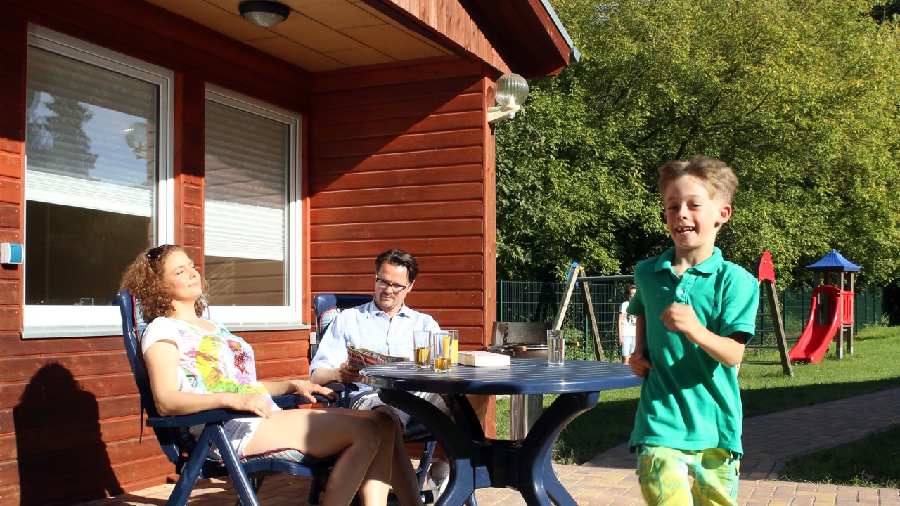 Familie genießt Urlaub vorm Bungalow