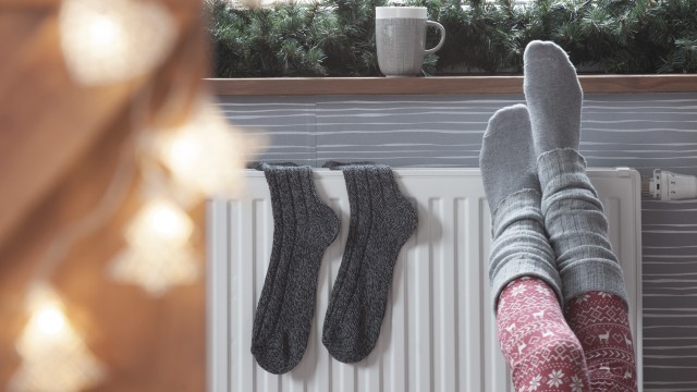 Frau wärmt ihre Füße an der Heizung im Winter, © NinaMalyna /Fotolia
