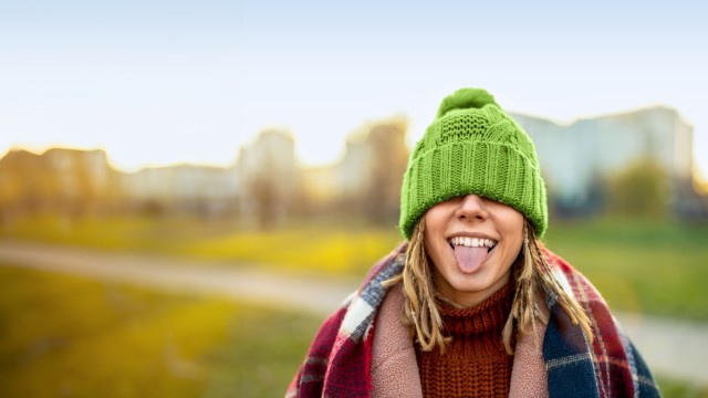 Porträt einer jungen Frau mit einem warmen Wintermantel, einen grünen Strickmütze und Schal im Freien