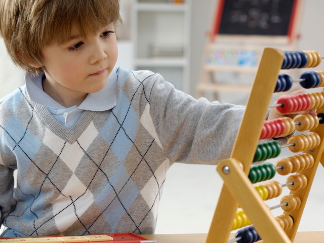 Kind mit Rechenschieber zählt Strom- und Gasrechnung nach, © acilo /iStock