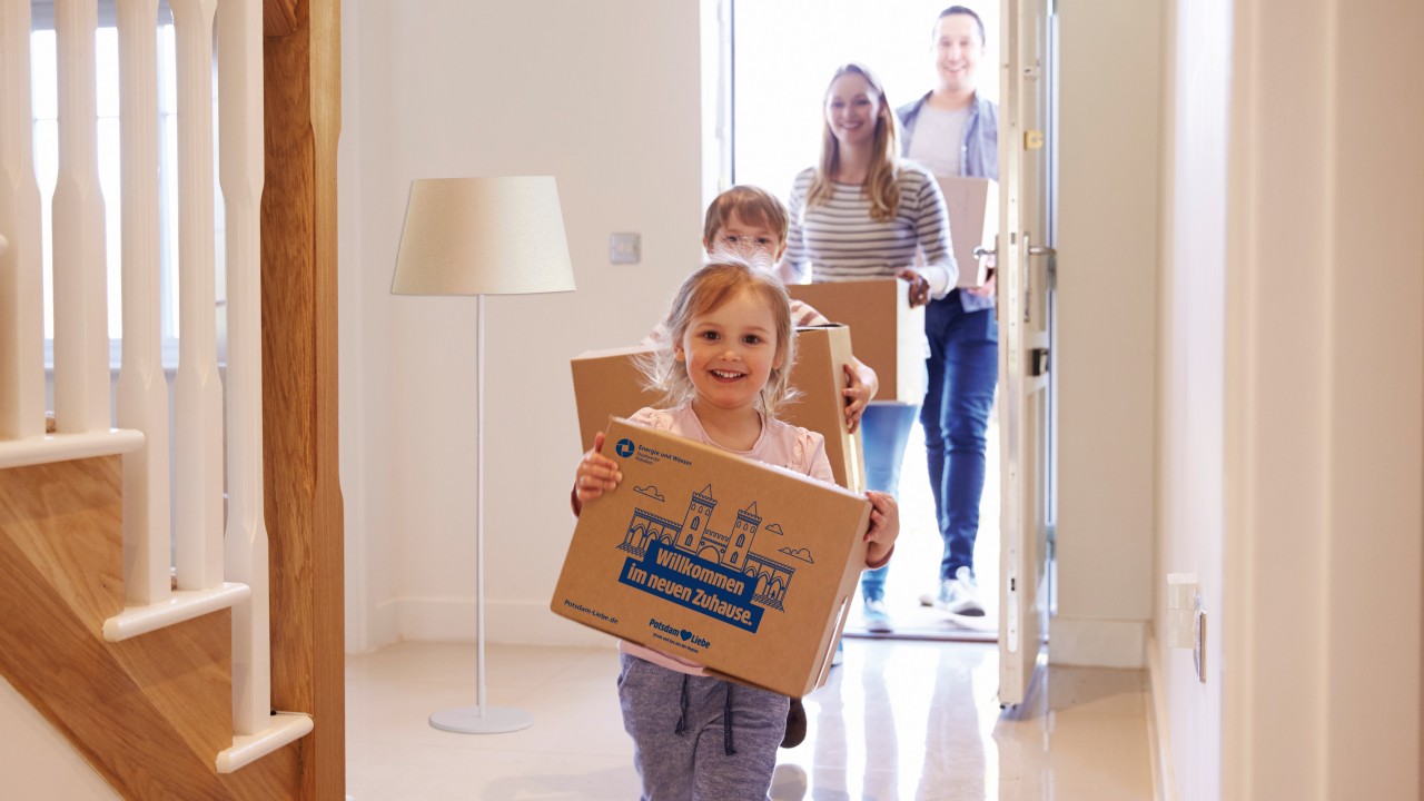 Junge Famiile betritt neue Wohnung mit Umzugkartons in den Händen