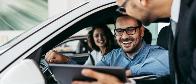 Mann und Frau sitzen im Auto und schauen auf ein Tablet, © AdobeStock