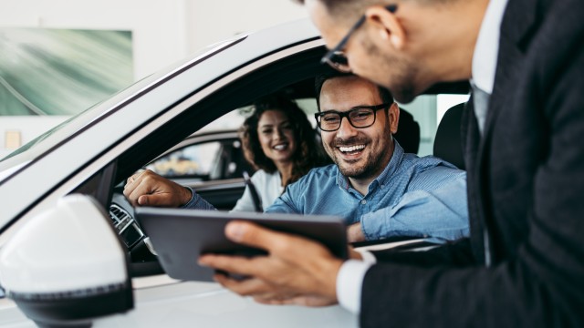 Mann und Frau sitzen im Auto und schauen auf ein Tablet, © AdobeStock