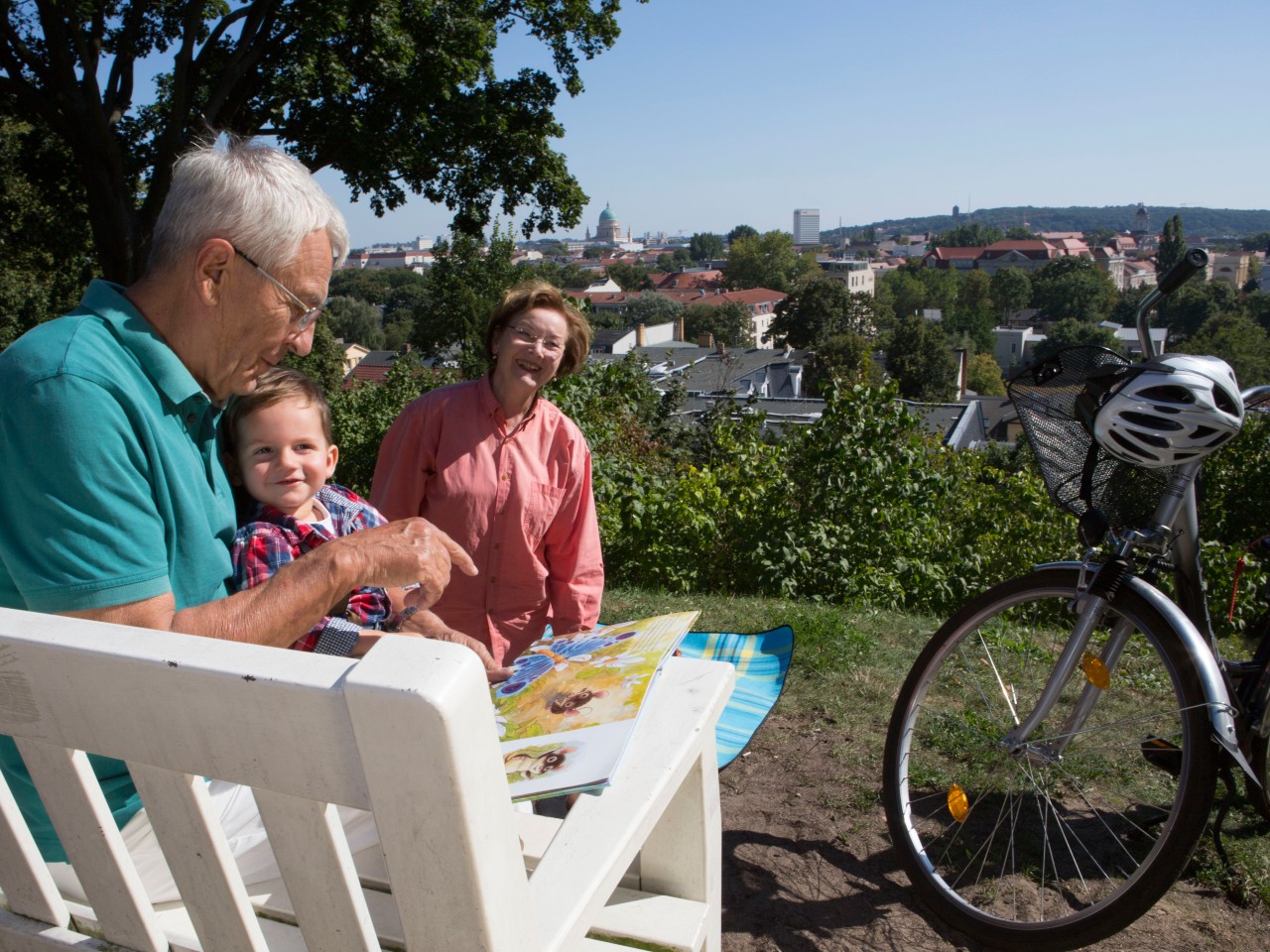 Großeltern mit dem Enkel sitzen auf einer weißen Bank mit dem Blick auf Potsdam, © Kathleen Friedrich